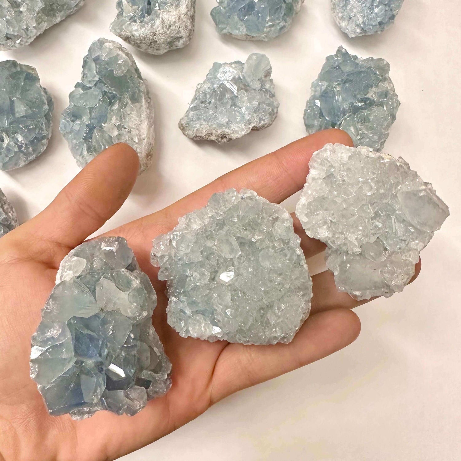 Hand holding three beautiful blue crystal clusters, showcasing natural formations with clear points and textures.