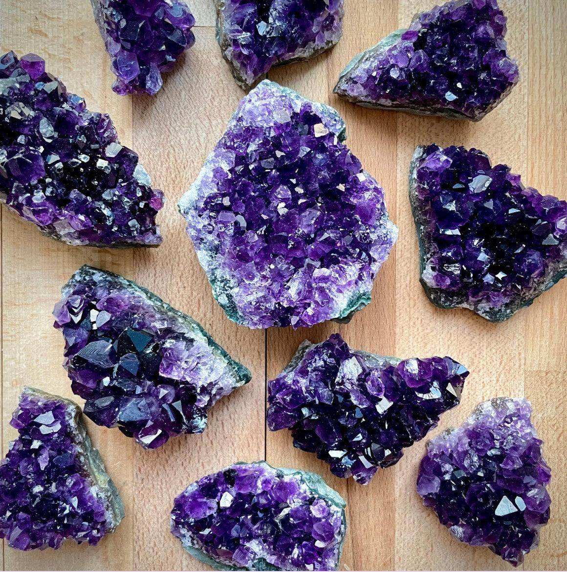 Collection of beautiful amethyst crystals displaying deep purple hues and natural sparkle on a wooden surface.
